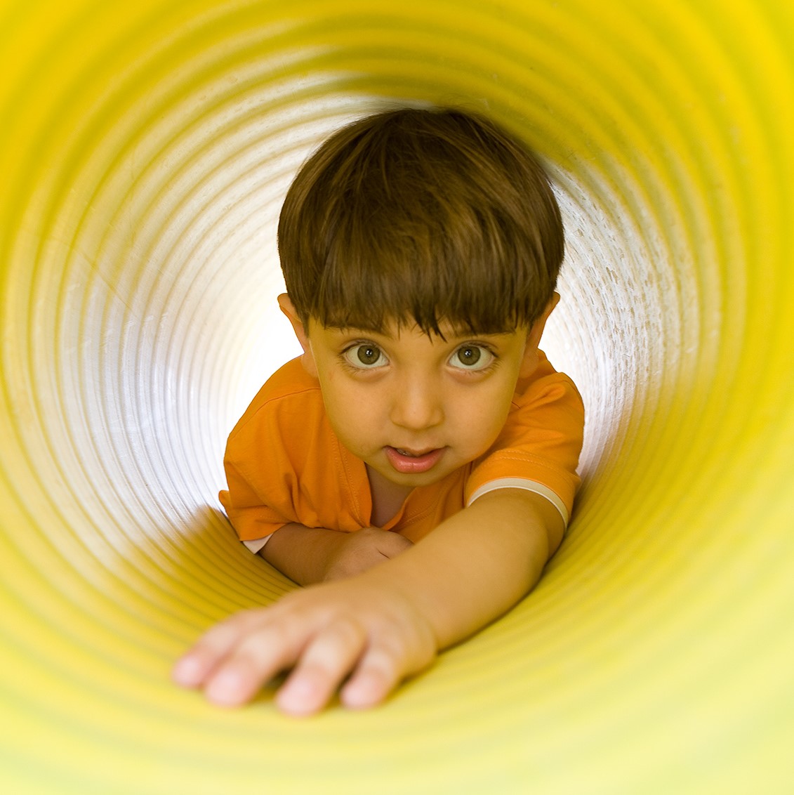 Young boy crawling through a play tunnel